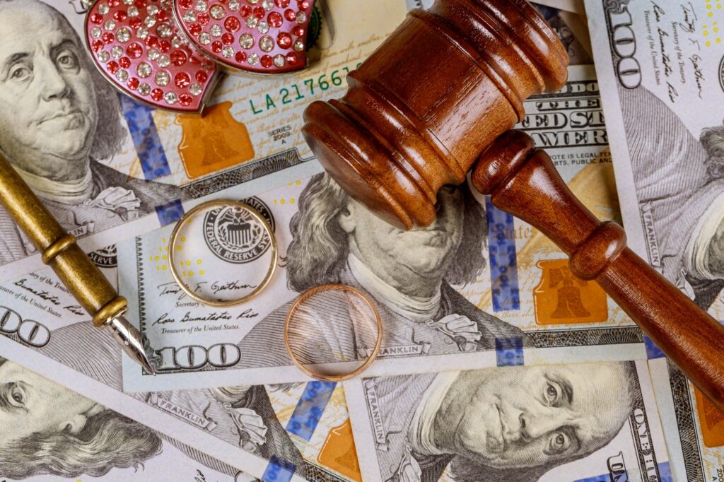 Close up of wedding rings and judge gavel on american dollars banknotes divorce concept